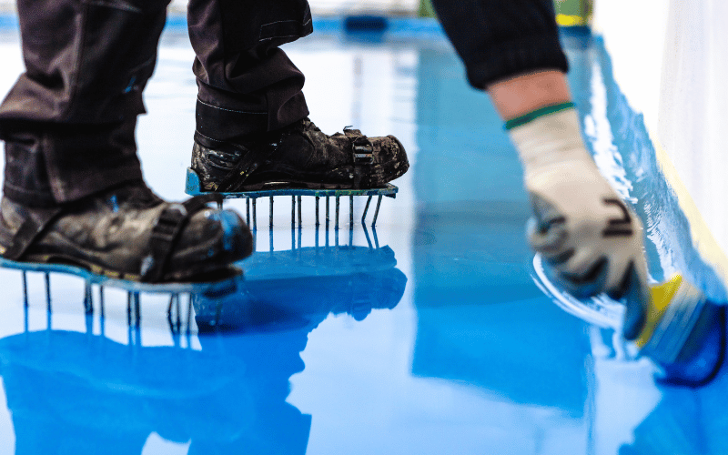 worker putting down new blue epoxy floor